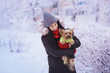 Attractive young woman having fun outside in snow with her dog Yorkshire Terrier. Young woman with a cute dog